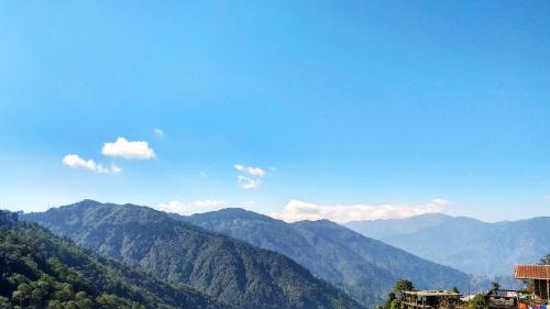een uitzicht op de bergen met een blauwe lucht en wolken bij Sunshraya Homestay in Darjeeling
