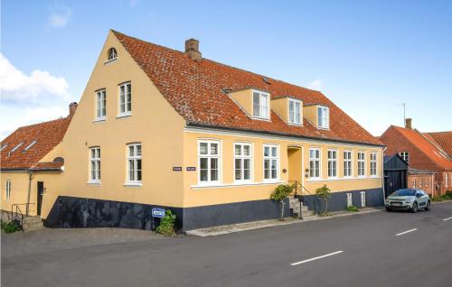 a yellow house with a red roof on a street at Cozy Apartment In Svaneke With Wifi in Svaneke