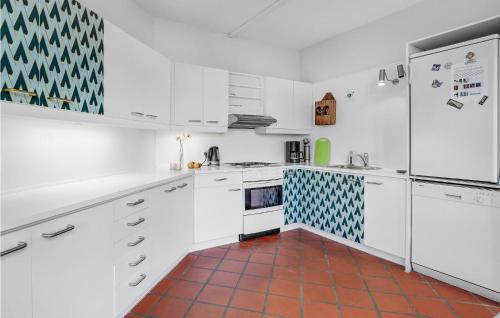 a kitchen with white cabinets and a red tile floor at Cozy Apartment In Svaneke With Wifi in Svaneke