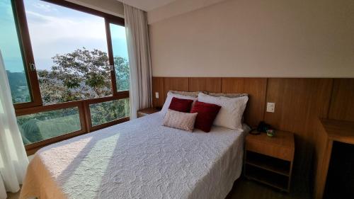 a bedroom with a bed with red pillows and a window at Loft 335 Vista Azul in Pedra Azul
