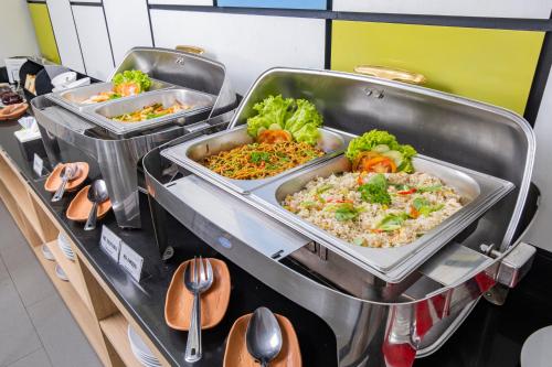 a buffet with three trays of food on a table at Hotel Citradream Bandung in Bandung