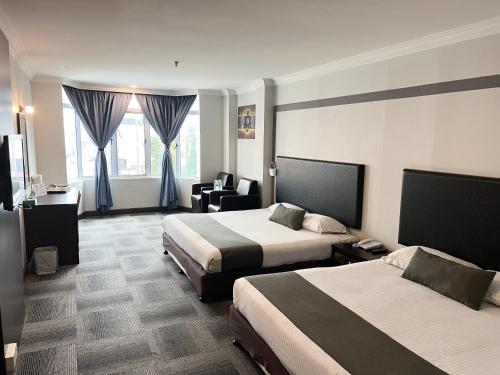 a hotel room with two beds and a chair at Legend Inn Taiping in Taiping