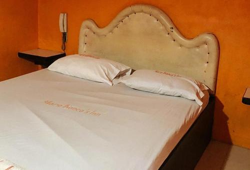 Maro Bianco's Inn Lubao Pampanga by RedDoorz في Lubao: سرير ابيض عليه وسادتين