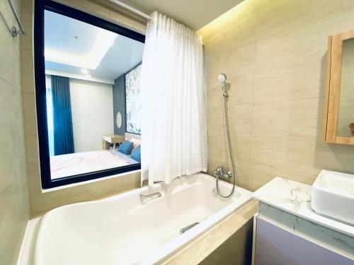 a bathroom with a tub and a sink and a mirror at Tony Apartment -FLC Sea Tower Quy Nhon in Quy Nhon