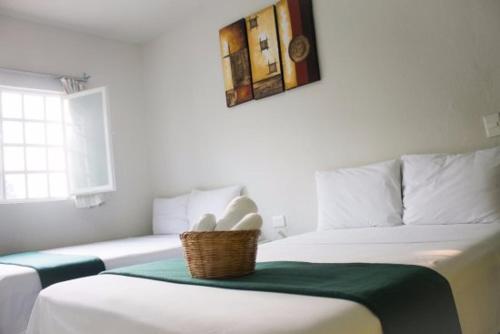 two beds in a room with a basket on the bed at Rosvel in Palenque