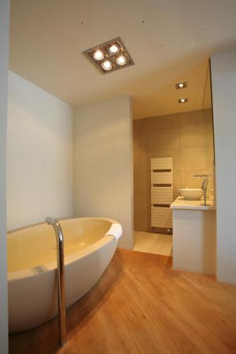 a bathroom with a large tub and a sink at Restaurant Hotel Merlet in Schoorl