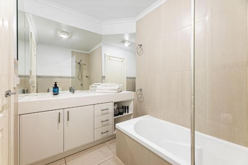 a white bathroom with a shower and a sink at Unit 8 Boardwalk Apartments in Narooma