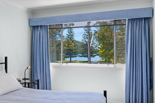 a bedroom with a large window with blue curtains at Unit 8 Boardwalk Apartments in Narooma
