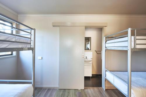 a bedroom with two bunk beds and a bathroom at NRMA Port Arthur Holiday Park in Port Arthur