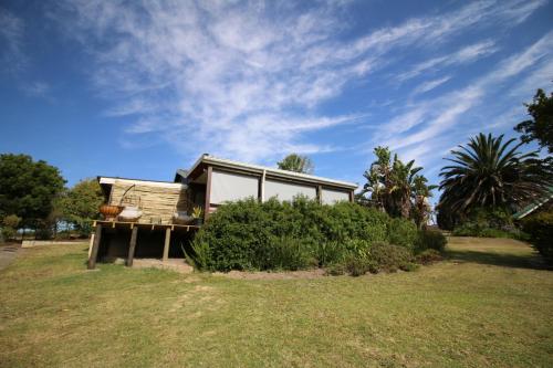 a house sitting on top of a grass field at The Wild Edge Last Light Cottage in Knysna