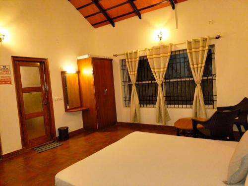 a living room with a table and chairs and a window at Belli bhavana by whitehouse homestay in Chikmagalur