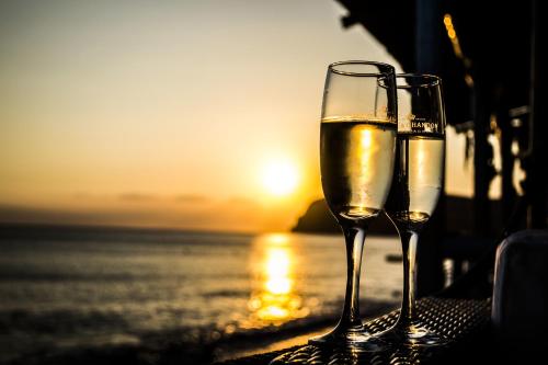 two glasses of wine sitting on a table near the ocean at Sappho Hotel in Skala Eresou