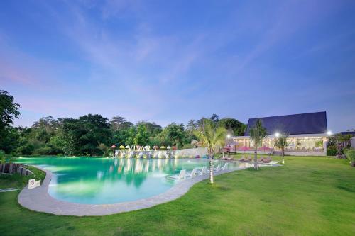 a large swimming pool with white chairs in a park at Vivara Bali Private Pool Villas & Spa Retreat in Jimbaran