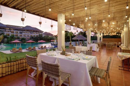 a restaurant with tables and chairs and a pool at Vivara Bali Private Pool Villas & Spa Retreat in Jimbaran