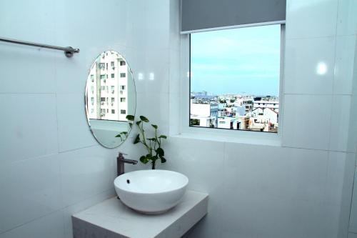 een witte badkamer met een wastafel en een raam bij HOTEL NGUYEN ANH in Ho Chi Minh-stad