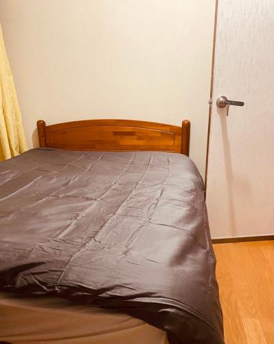 a bed with a gray comforter in a bedroom at アニメーションの起源地にある大泉学園ヴィラ in Katayama