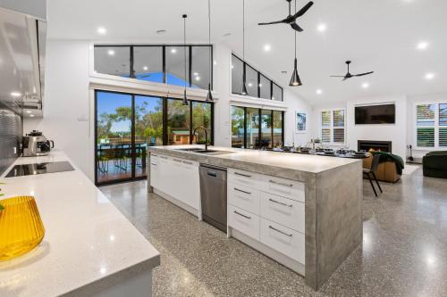 a large kitchen with white cabinets and a living room at Rio Vista - Luxury Accommodation in Rye