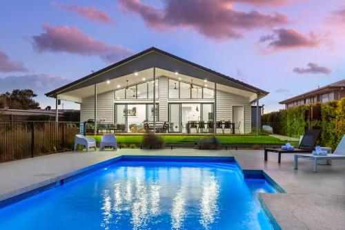 a house with a swimming pool in front of a house at Rio Vista - Luxury Accommodation in Rye