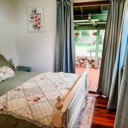 a bedroom with a bed and a large window at Mulberry Cottage in Mount Tamborine