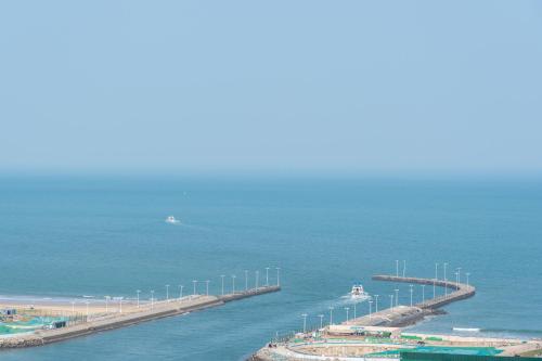 a pier in the ocean with a boat in the water at Cloud & Sea Boutique Apartment in Rizhao