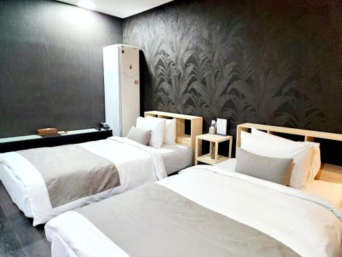 two beds in a hotel room with white sheets at JS Boutique Hotel in Hwaseong