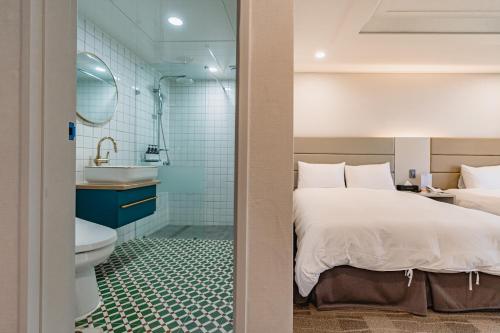 a bedroom with a bed and a bathroom with a sink at Cocoon Hotel in Jeju