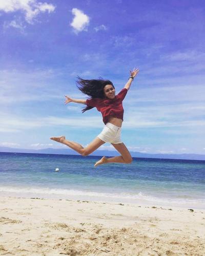 a woman jumping in the air on the beach at Lambug Beach Homestay in Lambug