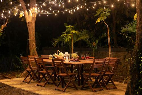 a wooden table with chairs and lights at StayVista at The Charcoal Villa Luxury Collection in Alibaug