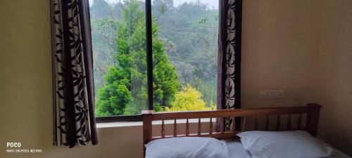 a bedroom with a bed and a large window at Vagamon Misty Holiday Home in Vagamon