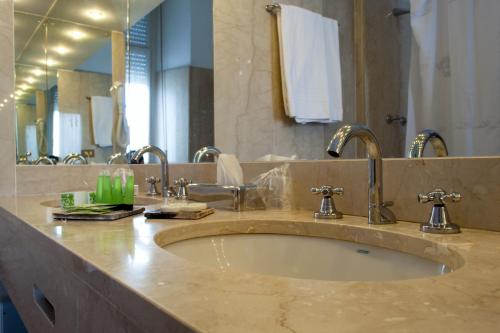 a bathroom with a sink and a large mirror at Palace Grand Hotel Varese in Varese