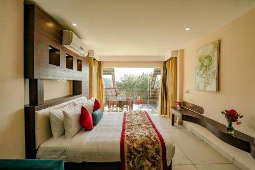 a hotel room with a bed and a balcony at Regenta Resort Exotica Dharamshala on Hilltop in Dharamshala