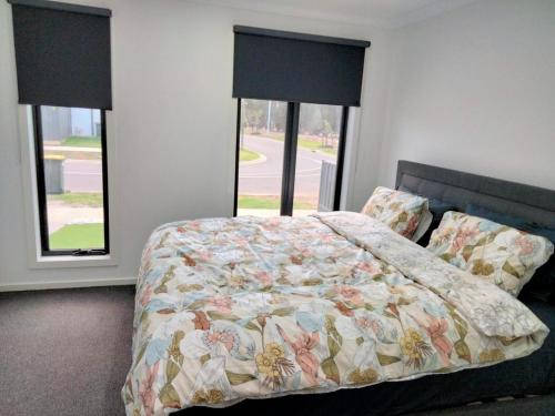 セント・レオナルズにあるModern and cosey 4 bedroom house walk to beachのベッドルーム1室(キルトベッド1台、窓2つ付)