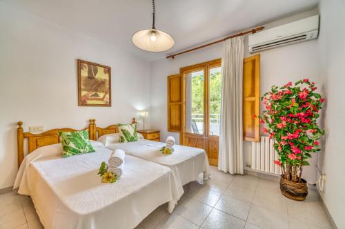 two beds in a room with a vase of flowers at Ideal Property Mallorca - Sirenas in Playa de Muro