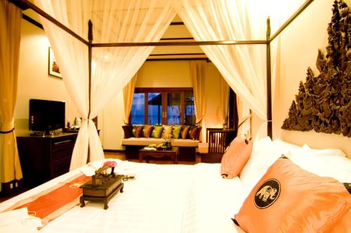 a bedroom with a large white bed with curtains at Kanok Buri Resort in Lipa Noi