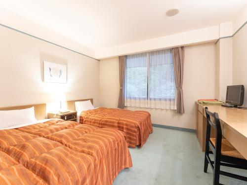 ein Hotelzimmer mit 2 Betten und einem TV in der Unterkunft Tabist Yabuki Golf Club in Yabuki