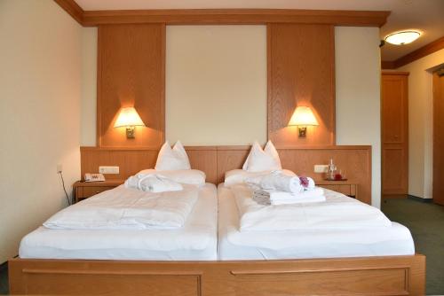 2 camas en una habitación con sábanas y almohadas blancas en Classic Rooms by Crystal, en Sankt Johann in Tirol