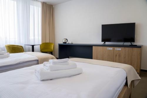 a hotel room with two beds and a flat screen tv at Wellness hotel Mestská plaváreň in Trebišov