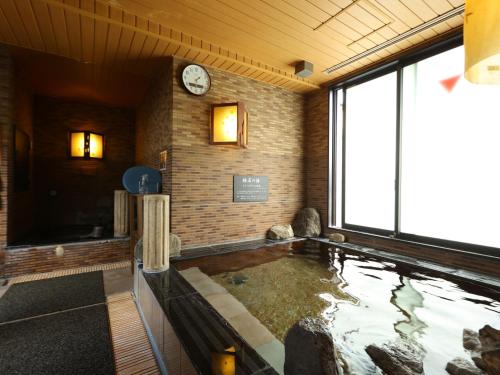 a large pool of water in a room with a clock at Dormy Inn Takasaki in Takasaki