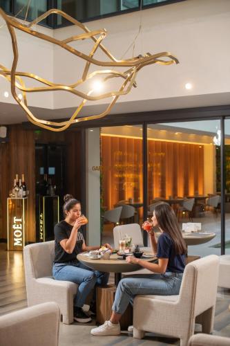 two people sitting at a table eating food at The Emporium Hotel Plovdiv - MGallery Collection in Plovdiv