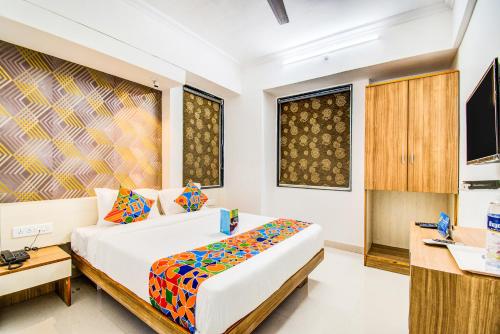 a bedroom with a bed and a desk and a television at FabExpress Marvel Bliss Viman Nagar in Pune