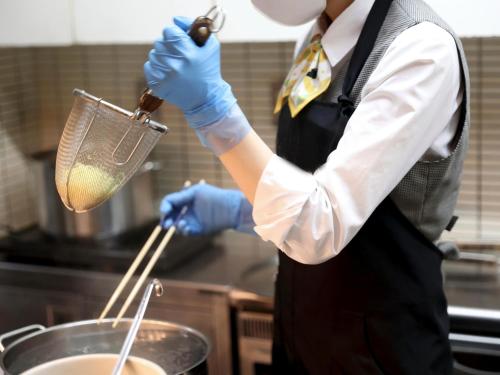 a man stirring a pot in a kitchen at Dormy Inn Takasaki in Takasaki