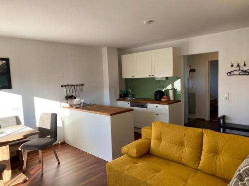 a living room with a yellow couch and a kitchen at Wohnung Steixner in Westendorf