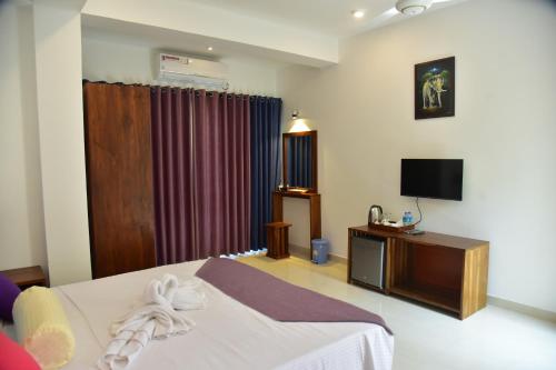 ein Hotelzimmer mit einem Bett und einem TV in der Unterkunft Eden Grand in Dambulla