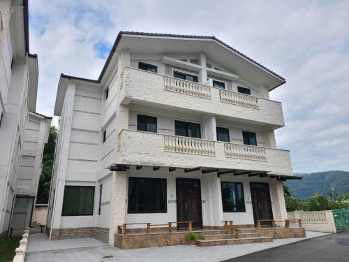 ein weißes Gebäude mit zwei Balkonen darüber in der Unterkunft Fay Homestay in Yilan
