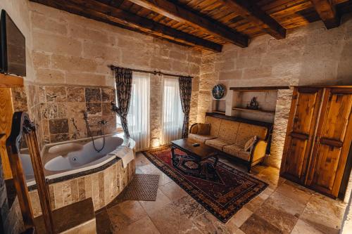 a bathroom with a large tub in a room with a couch at Hanzade Cappadocia in Goreme