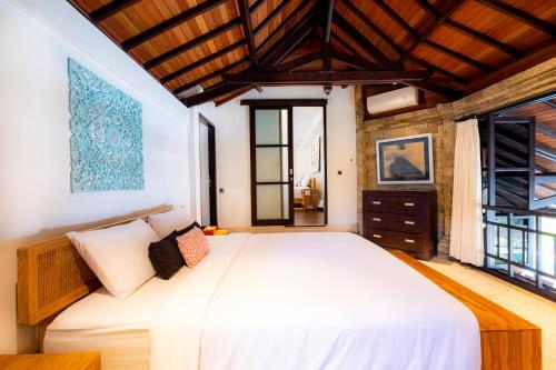 a bedroom with a large white bed and windows at Villa Frangipani Seminyak in Seminyak