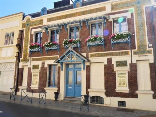 un bâtiment en briques avec une porte bleue et des boîtes de fleurs dans l'établissement Villa d'Eaux, à Villers-sur-Mer