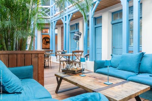 a patio with blue couches and a wooden table at Villa d'Eaux in Villers-sur-Mer