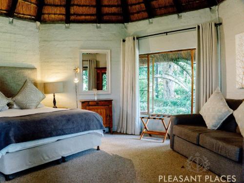 a bedroom with a bed and a couch and a window at Pleasant Places By Sanaandi in Lidgetton