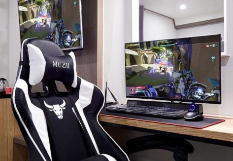 a desk with a computer monitor and a gaming chair at Boutique Hotel XYM in Suwon